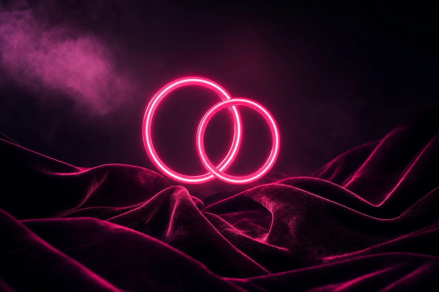 Two interlocking neon pink rings above dark velvet